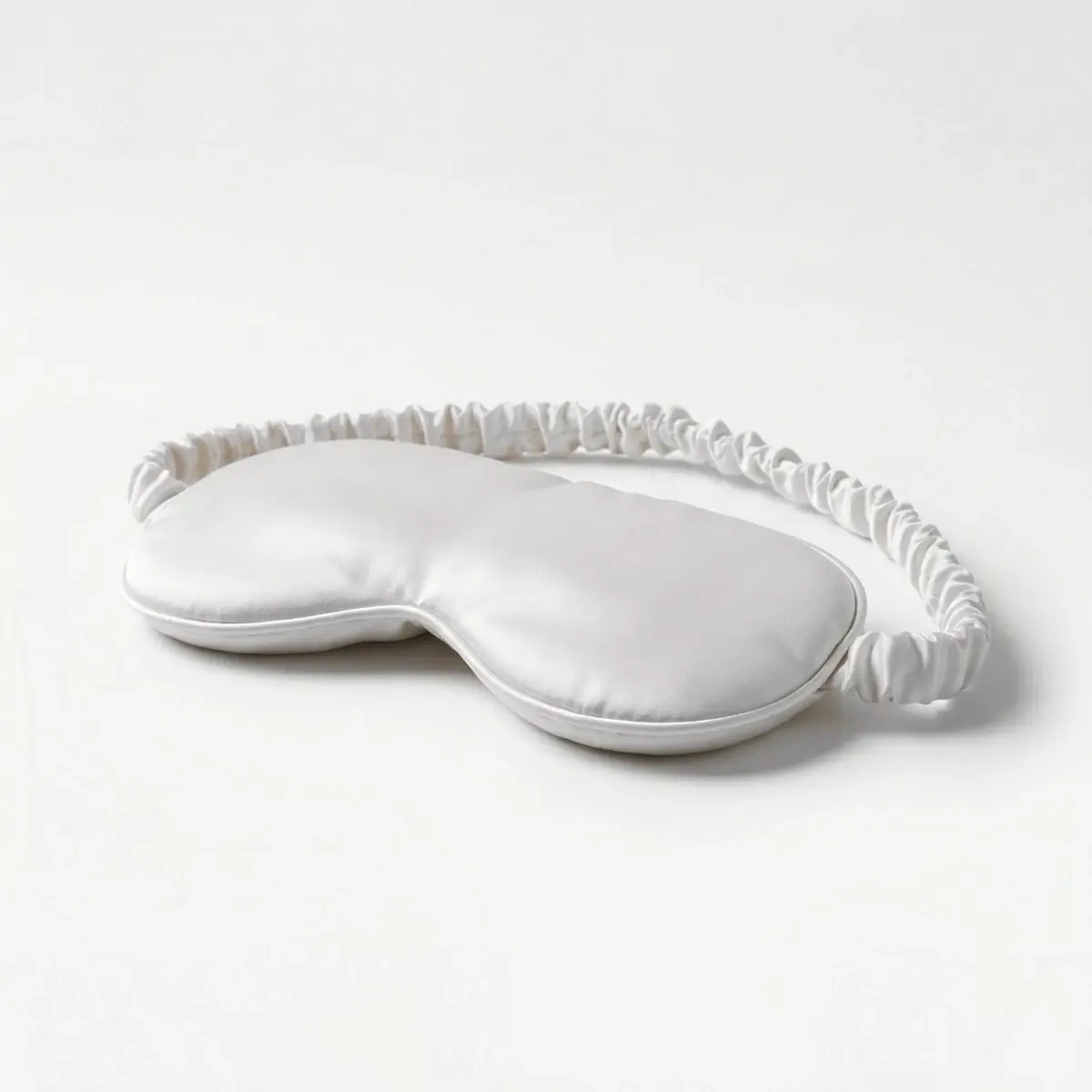 The Weighted Eye Mask in Ivory from the front, its padded body and gathered strap, the design target