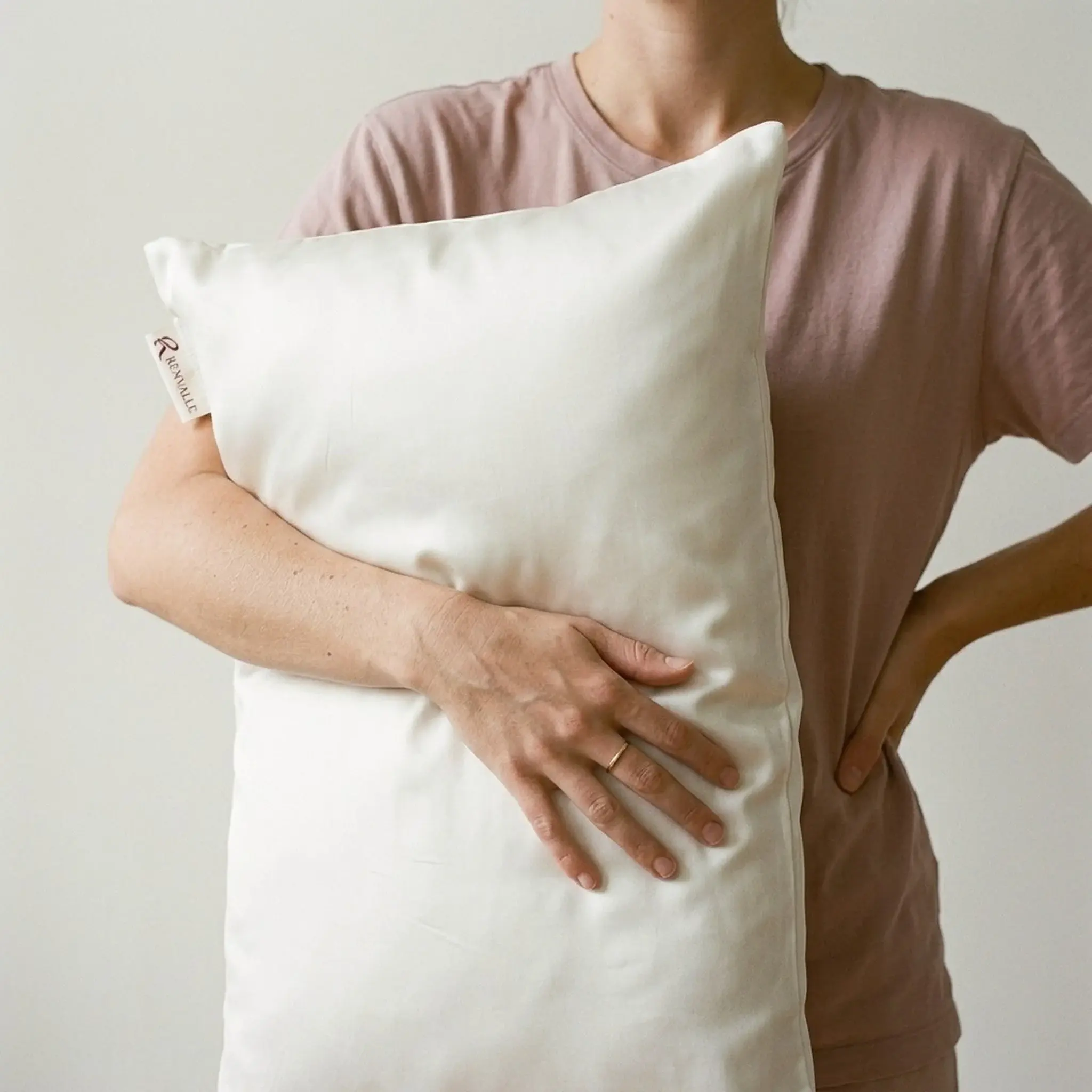 A woman carrying a pillow in the Ivory silk pillowcase under one arm