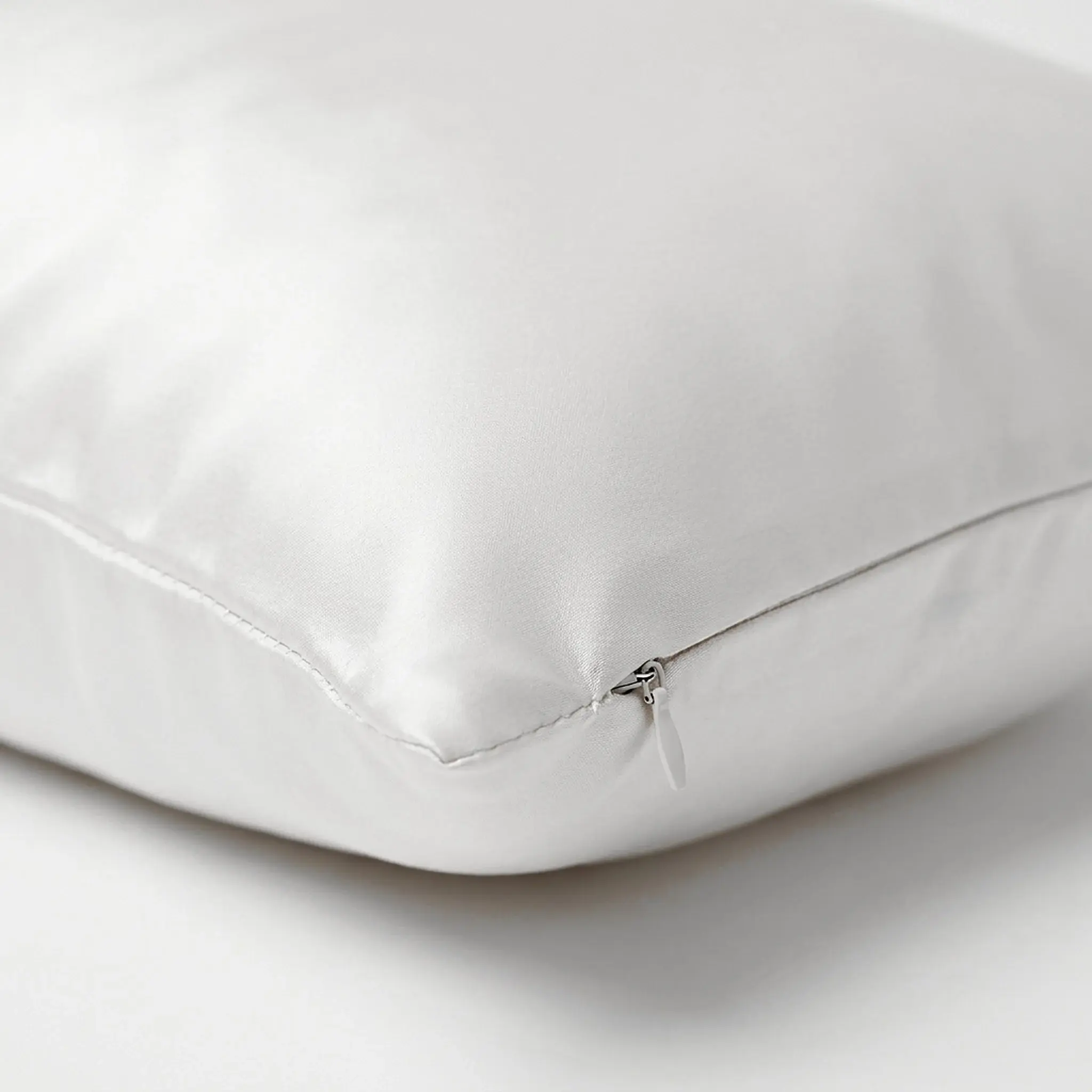 Close-up of the Ivory pillowcase's corner: the zip hidden in the side seam, only its small pull showing